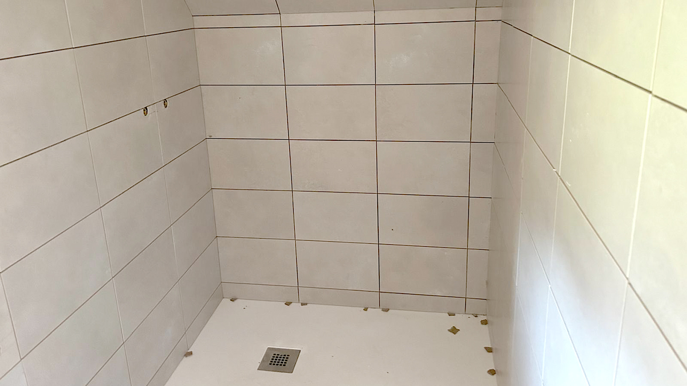 Douche à l'italienne ou cabine : pose de carrelage blanc moderne dans la salle d'eau.